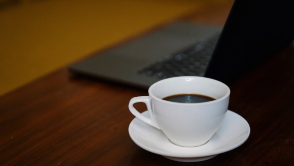 Meja kosong dengan laptop dan secangkir minuman dalam suasana tenang